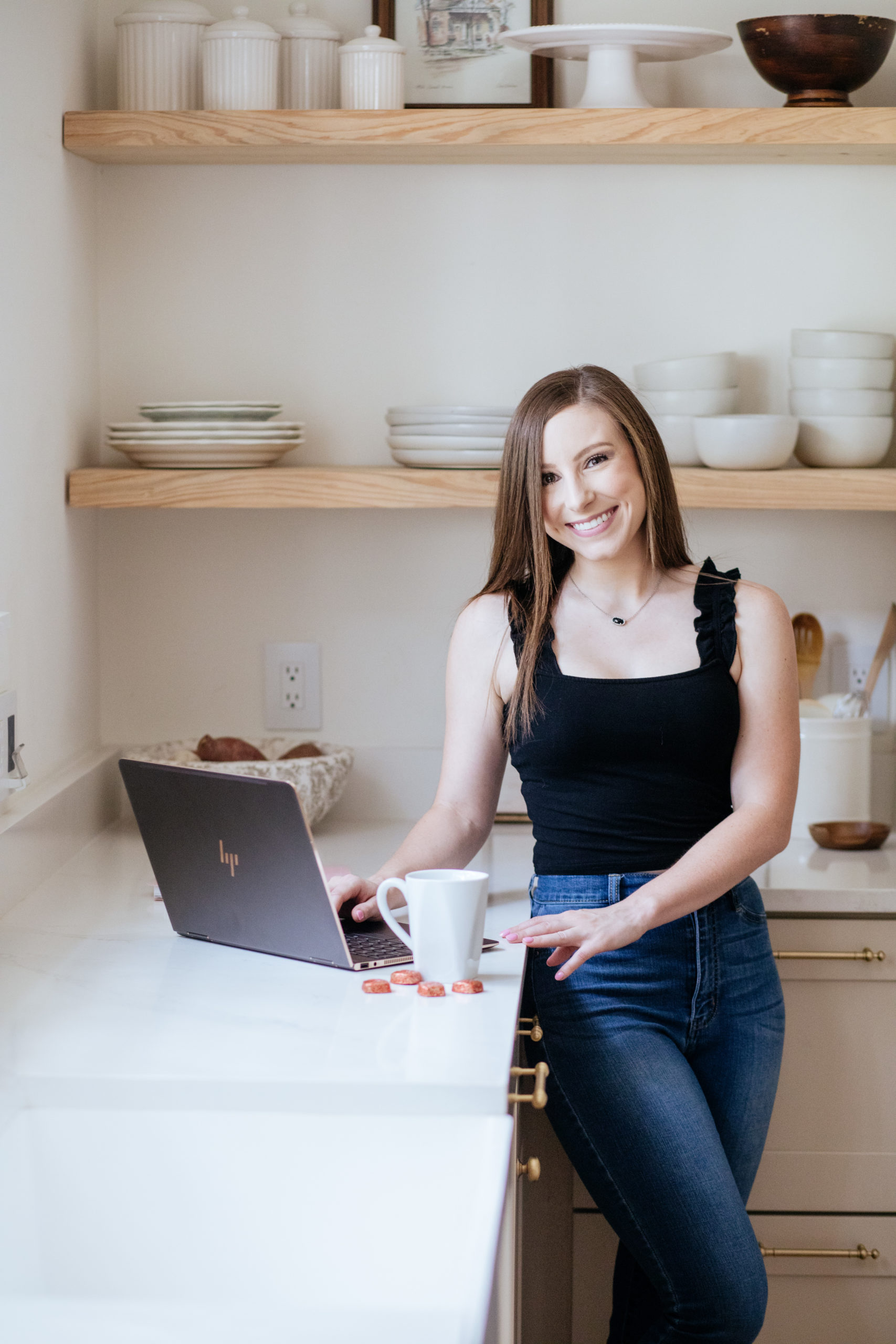 modern kitchen with woman drinking coffee and laptop